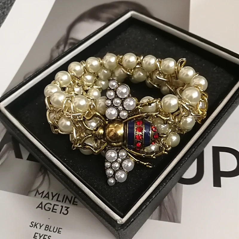 Pearl and gold bracelet with a bee design on a black box
