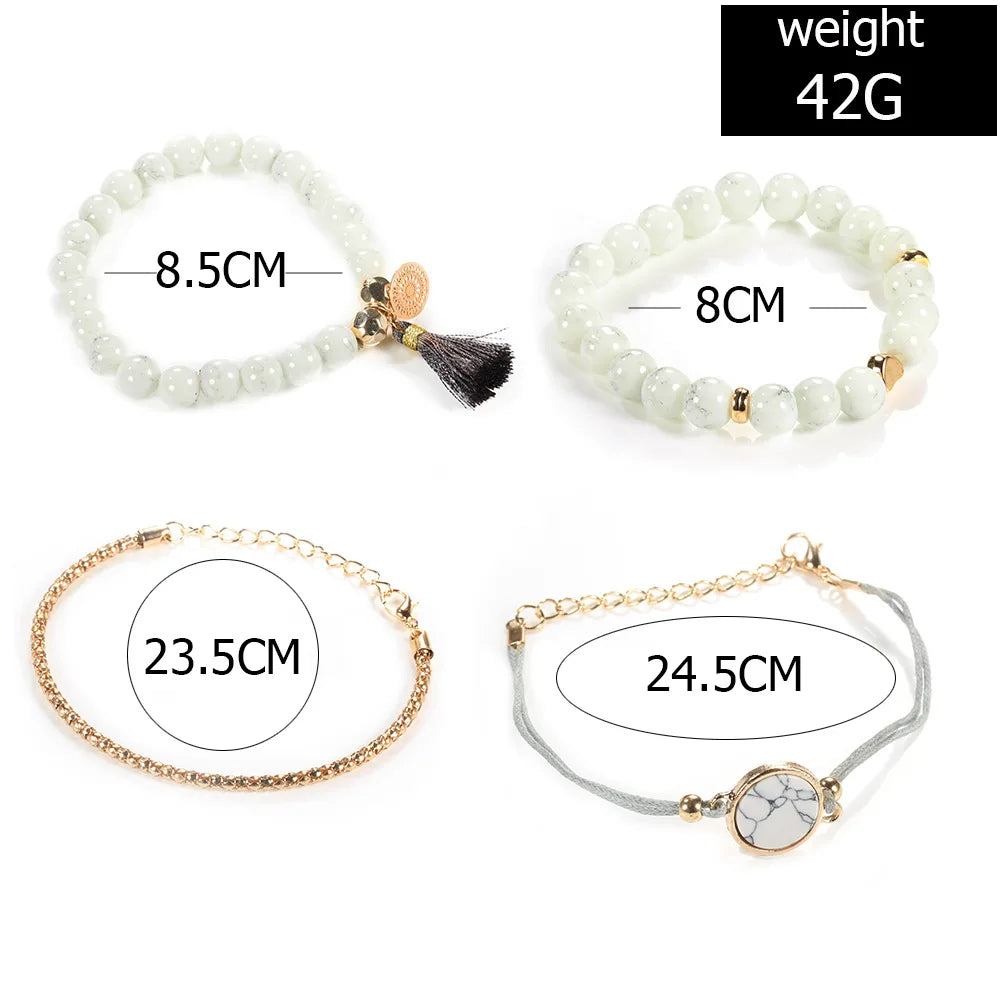 White beaded bangle bracelet set with gold-tone clasp, tassel charm, and chain bracelet