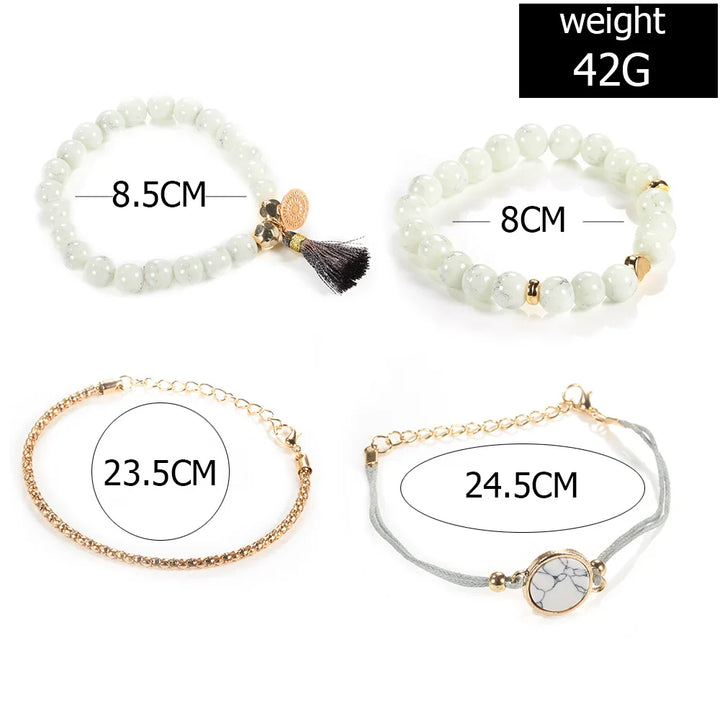 White beaded bangle bracelet set with gold-tone clasp, tassel charm, and chain bracelet