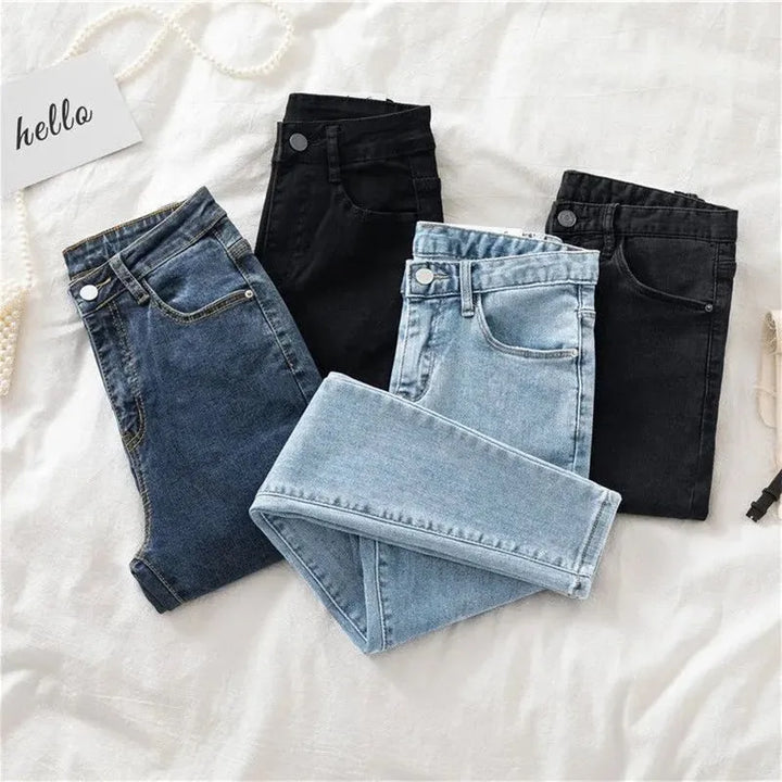 Folded blue and black jeans on a white surface with 'hello' card.