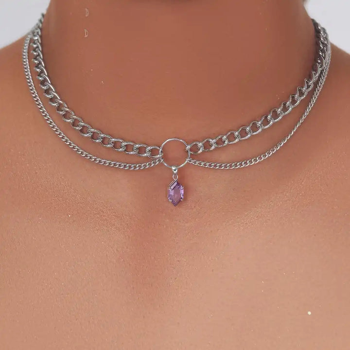Silver-tone double-chain necklace with round clasp and purple faceted teardrop pendant.
