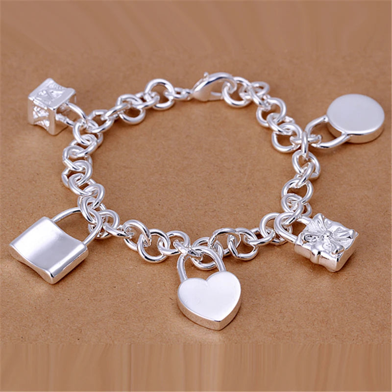 Silver charm bracelet with various charms on a brown background