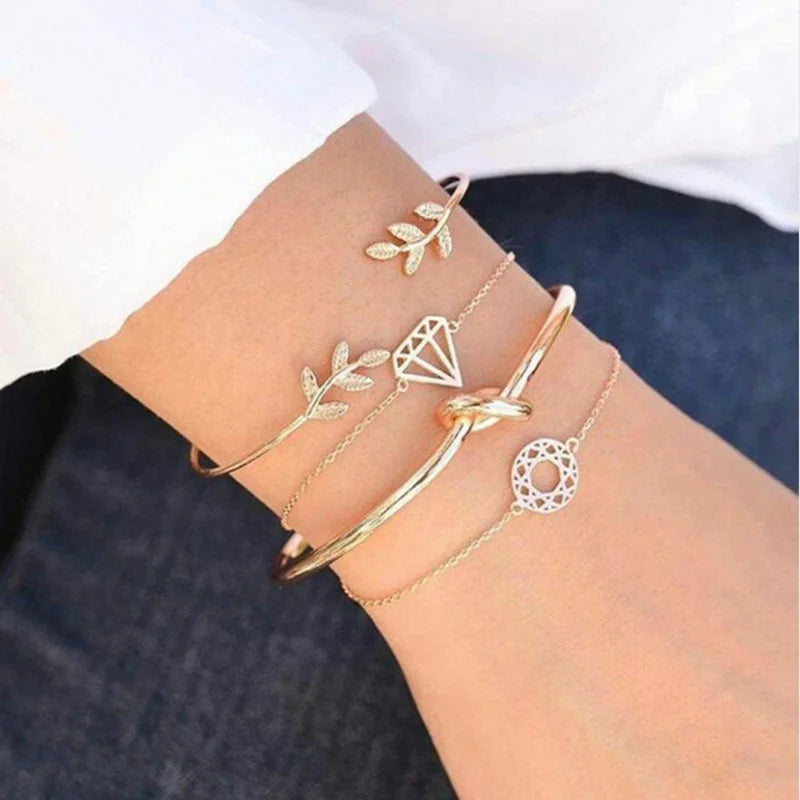 Gold-tone leaf and triangular charm bracelets with layered bangles and small heart detailing