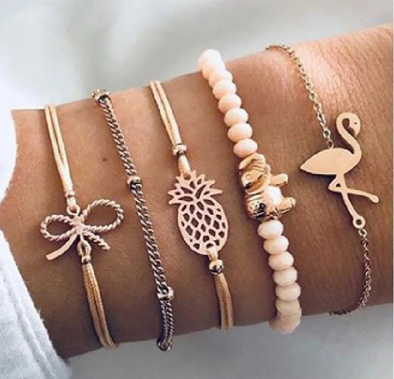 Gold-tone charm bracelet set with butterfly, pineapple, flamingo, and white bead strand
