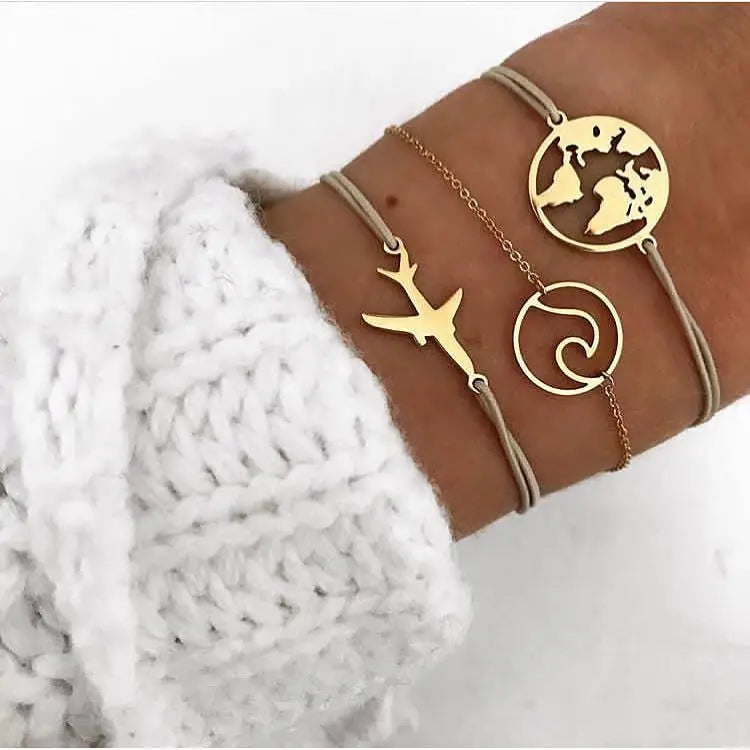 Gold-tone charm bangle set with world map, bird, and spiral pendants