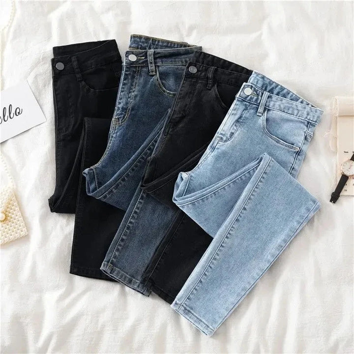 Three pairs of jeans in black, blue, and light wash on a white surface.