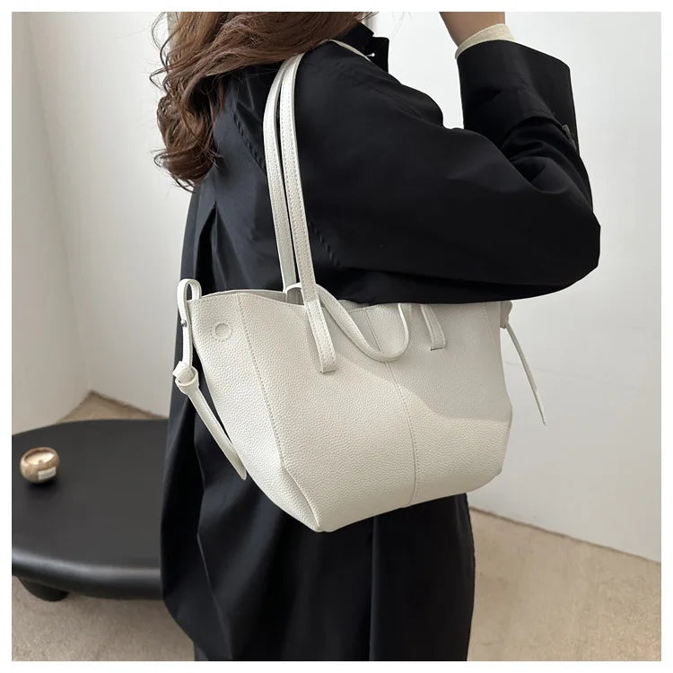 Person holding a white tote bag against a neutral background