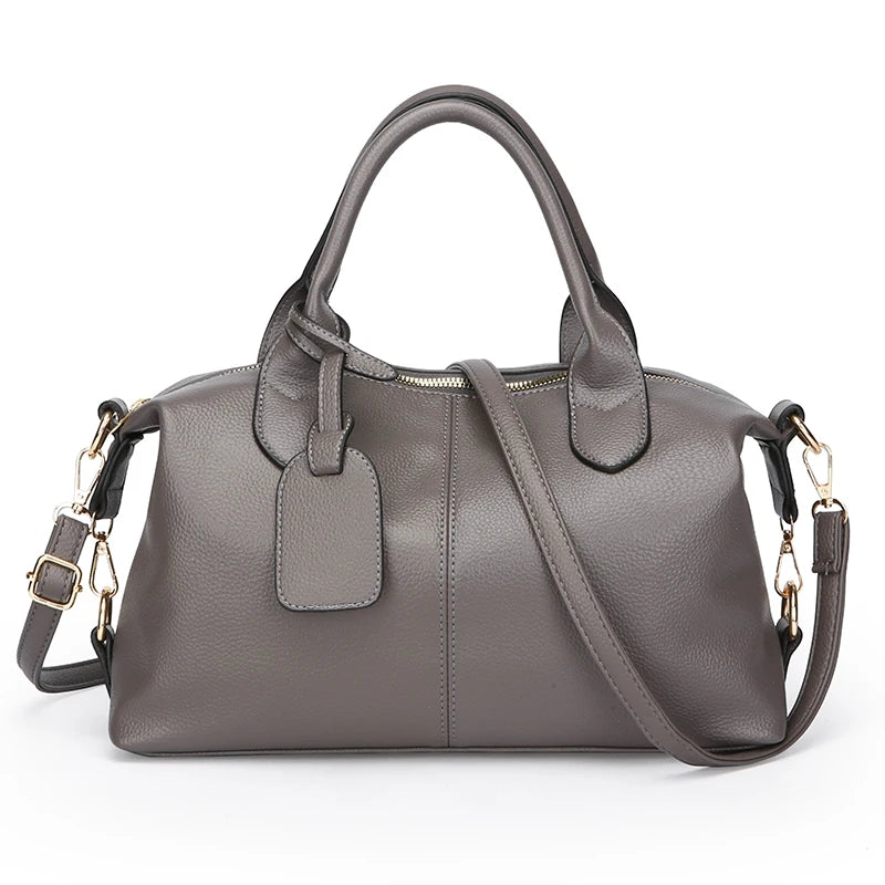 Gray soft leather tote bag with top handles, front luggage tag, and crossbody strap