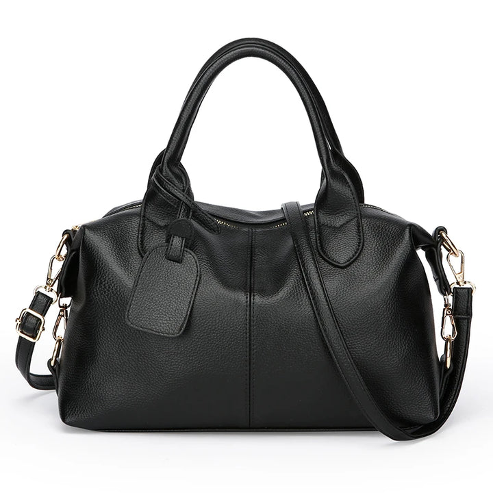 Black soft leather tote bag with top handles, front luggage tag, and side strap