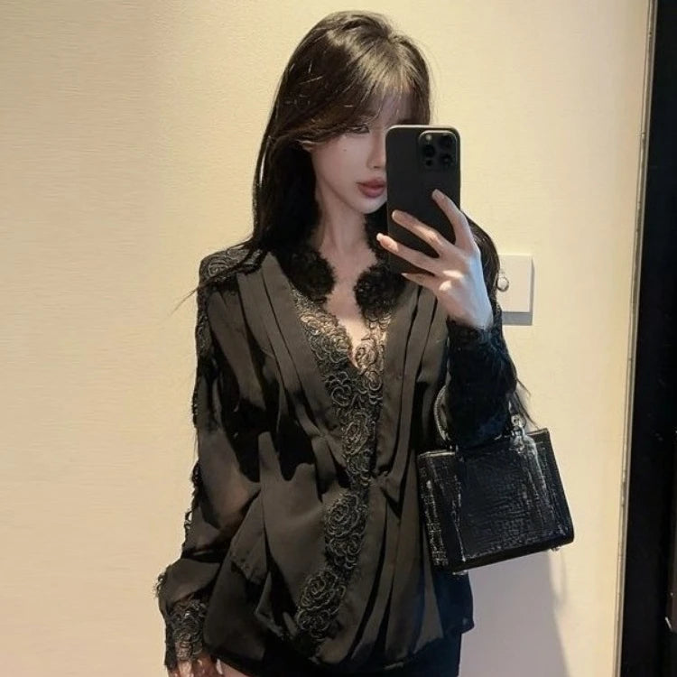 Woman taking a mirror selfie wearing a black lace top and holding a black handbag.