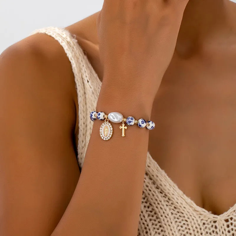 Close-up of a person's arm wearing a bracelet with various charms against a neutral background