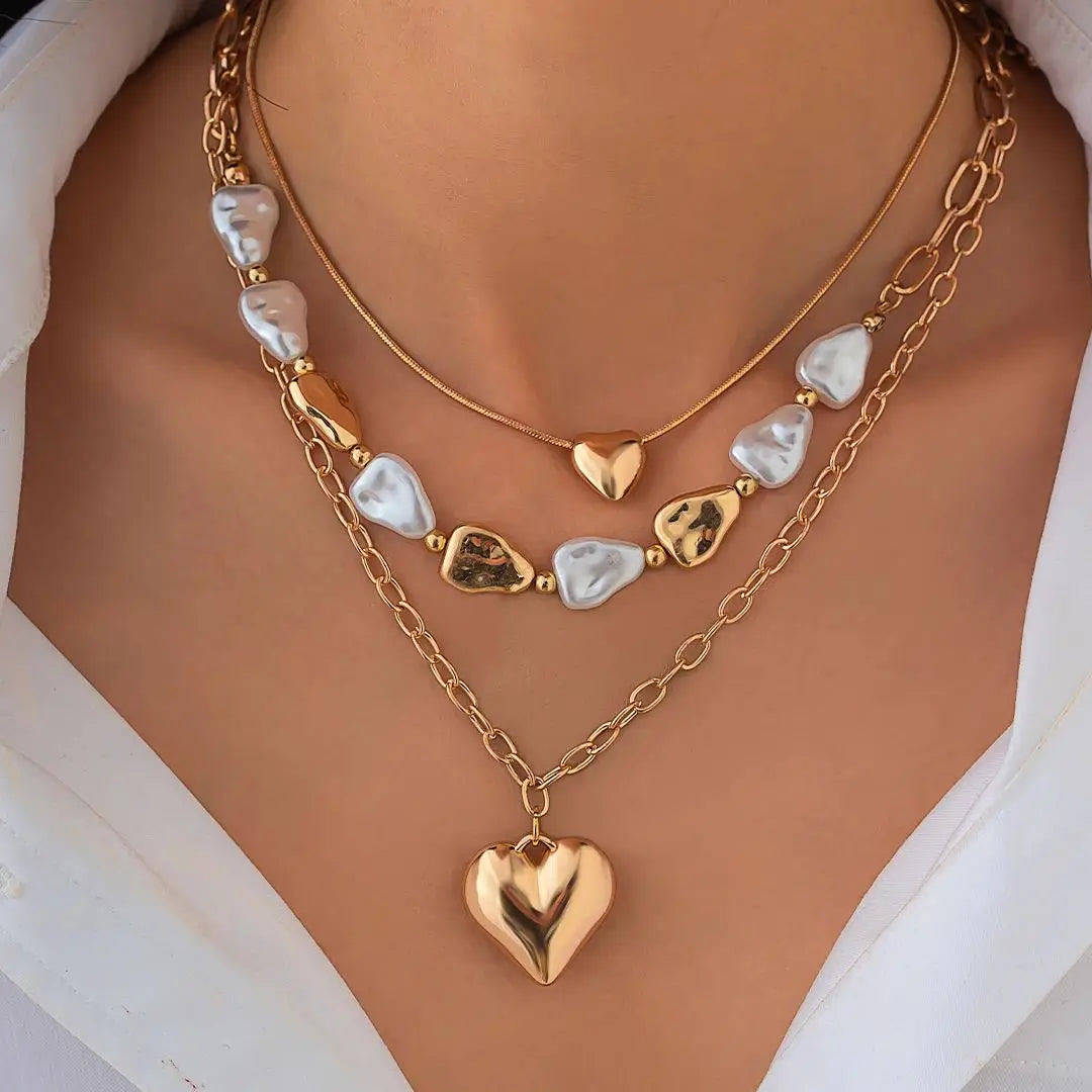 Gold heart-shaped necklace with white stones on a model wearing a white top.