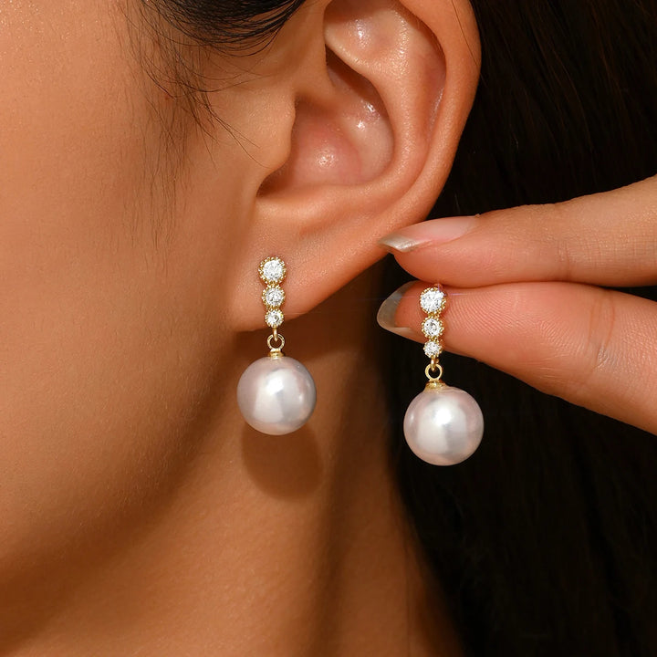 Gold-plated zircon and pearl drop dangle earrings, close-up on ear