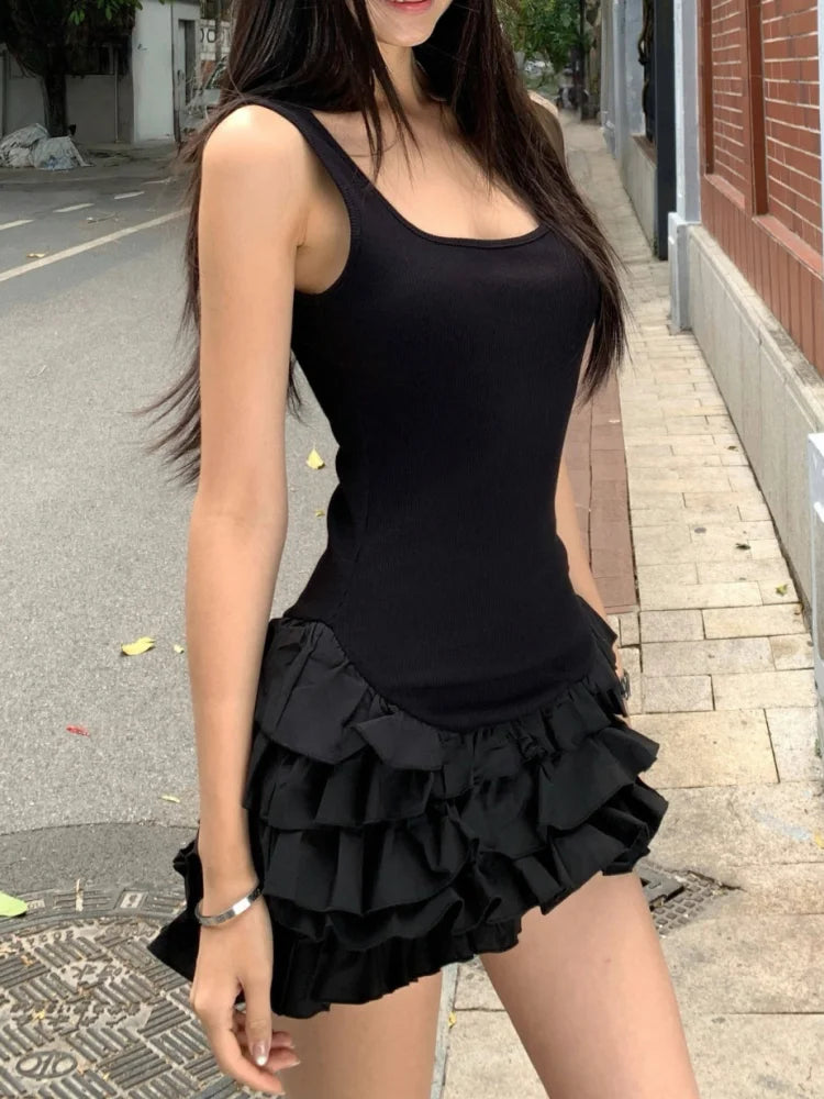 Woman wearing a black sleeveless top and ruffled black skirt on a street.