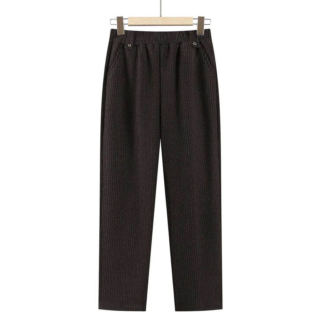 Dark brown vertically ribbed wide-leg cropped pants with an elastic waistband and button details, hanging on a wooden hanger against a white background.