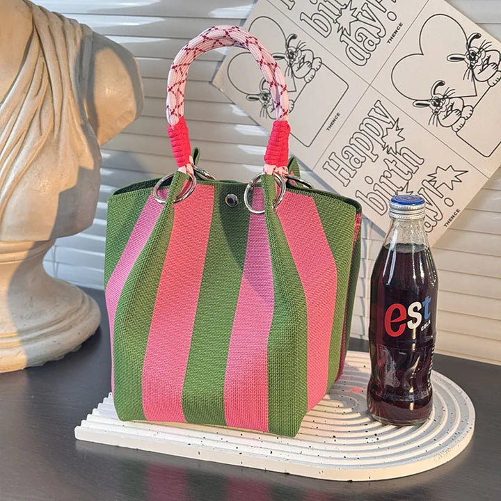 Green and pink striped satchel bag with red/white braided top handle straps.