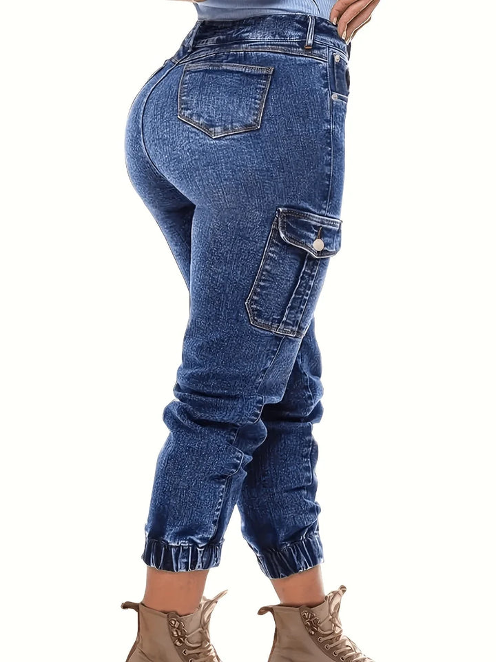 Dark blue high-waist denim jeans with reinforced side cargo pockets and ankle cuffs.