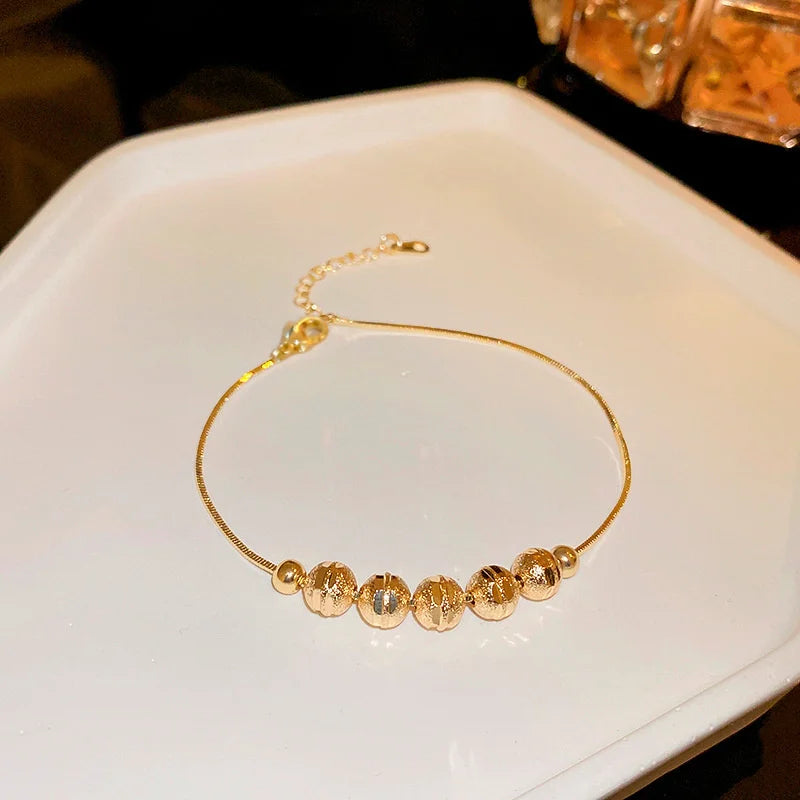 Gold-tone beaded bracelet with small oval zircon accents and round bead stations
