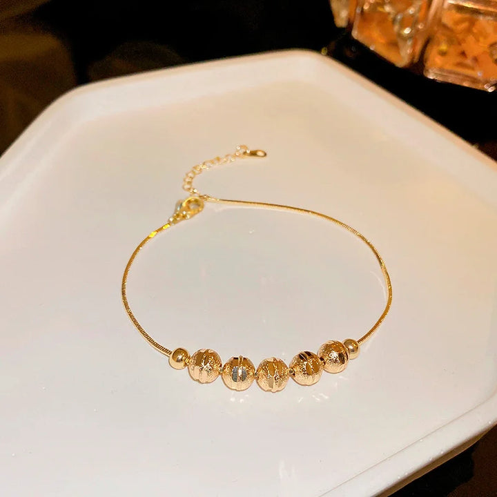 Gold-tone beaded bracelet with small oval zircon accents and round bead stations