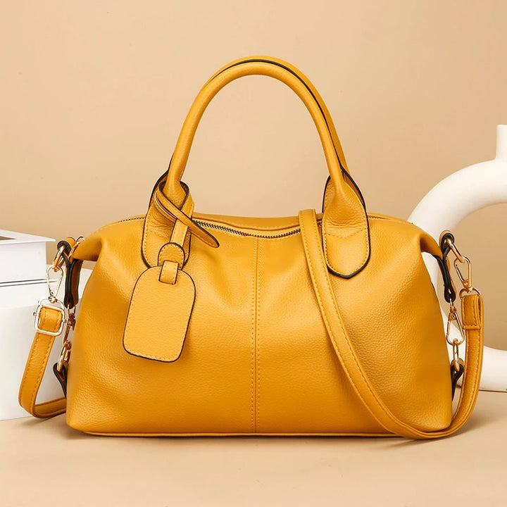 Women's soft leather tote bag in yellow with top handles and shoulder strap