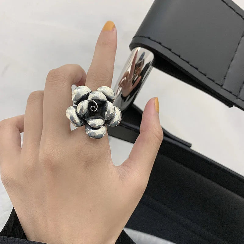 Silver 925 flower ring with dark center bead and curved petal edges, side angle