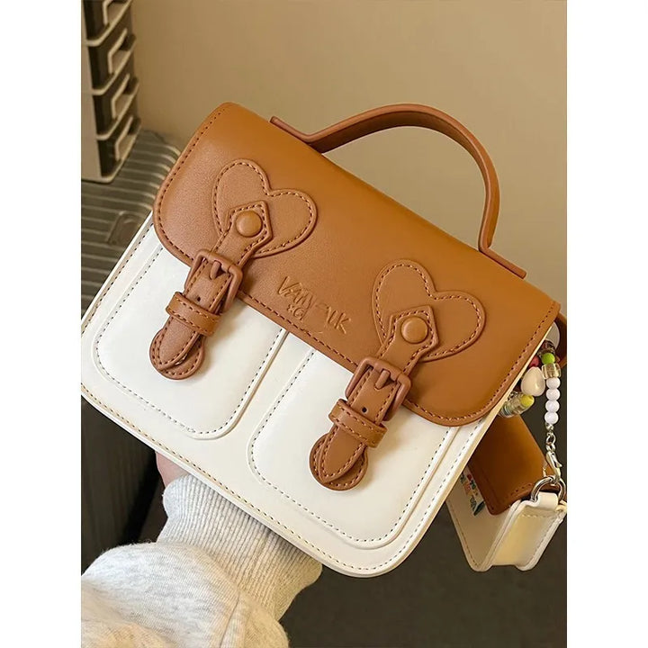 Two-tone women’s leather-look handbag with heart flap and adjustable strap details