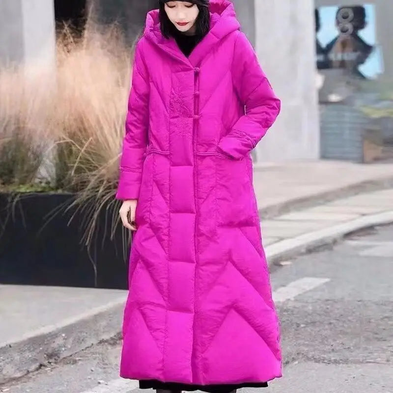 Person wearing a long pink coat on a city street.