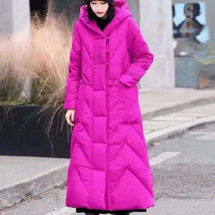 Person wearing a long pink coat on a city street.