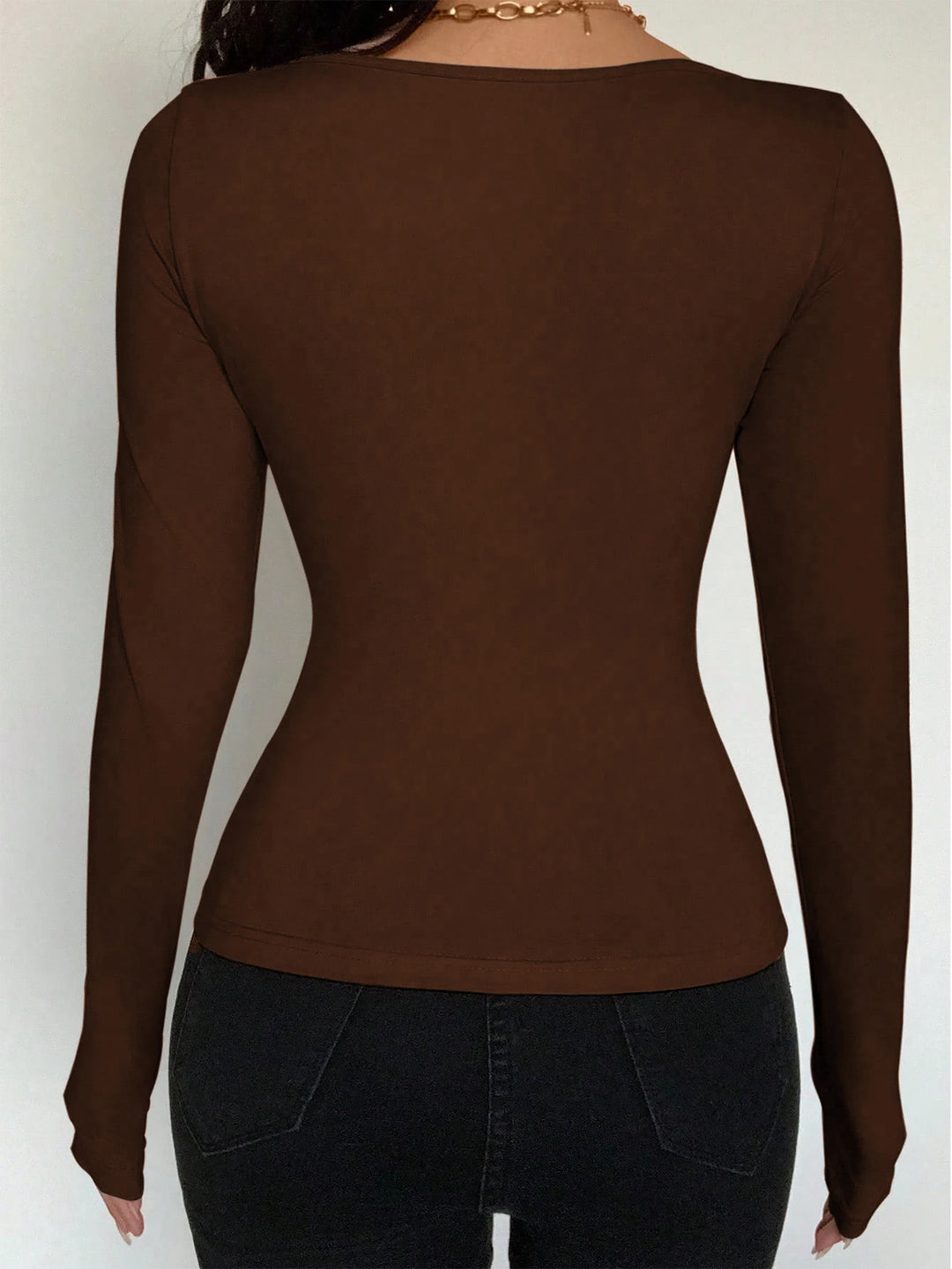 Brown long-sleeve top worn by a person on a white background