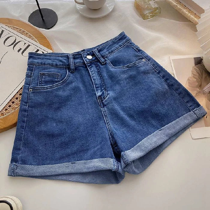 Blue denim shorts on a light surface with a magazine and cup in the background