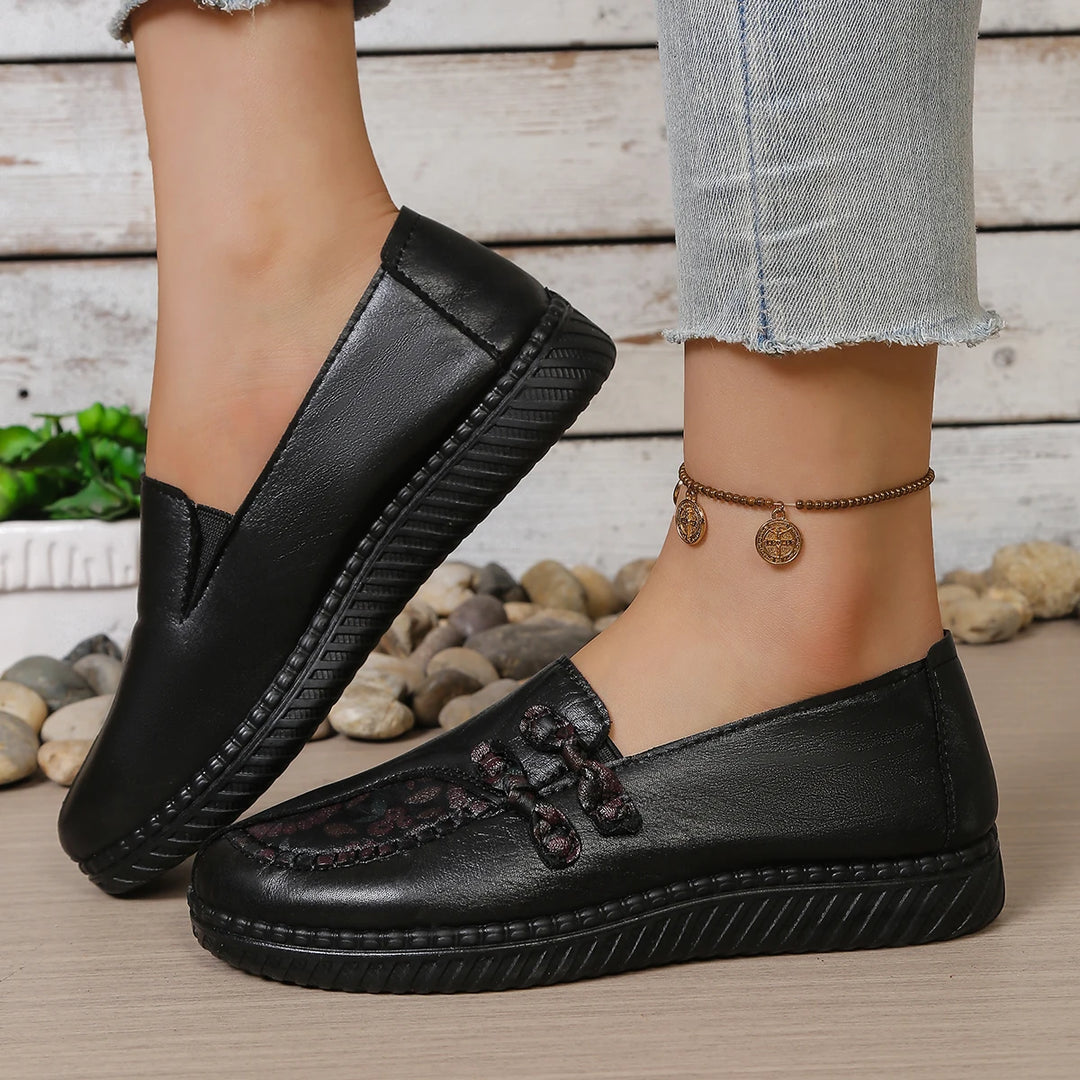 Black leather slip-on mules with butterfly-knot lace bow and textured sidewall stitching