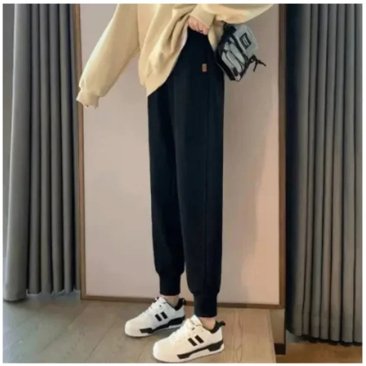 Women's Black Tapered Cuffed Joggers, Standing View With White Sneakers