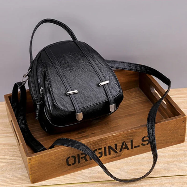 Black leather backpack on a wooden tray with 'ORIGINALS' branding.