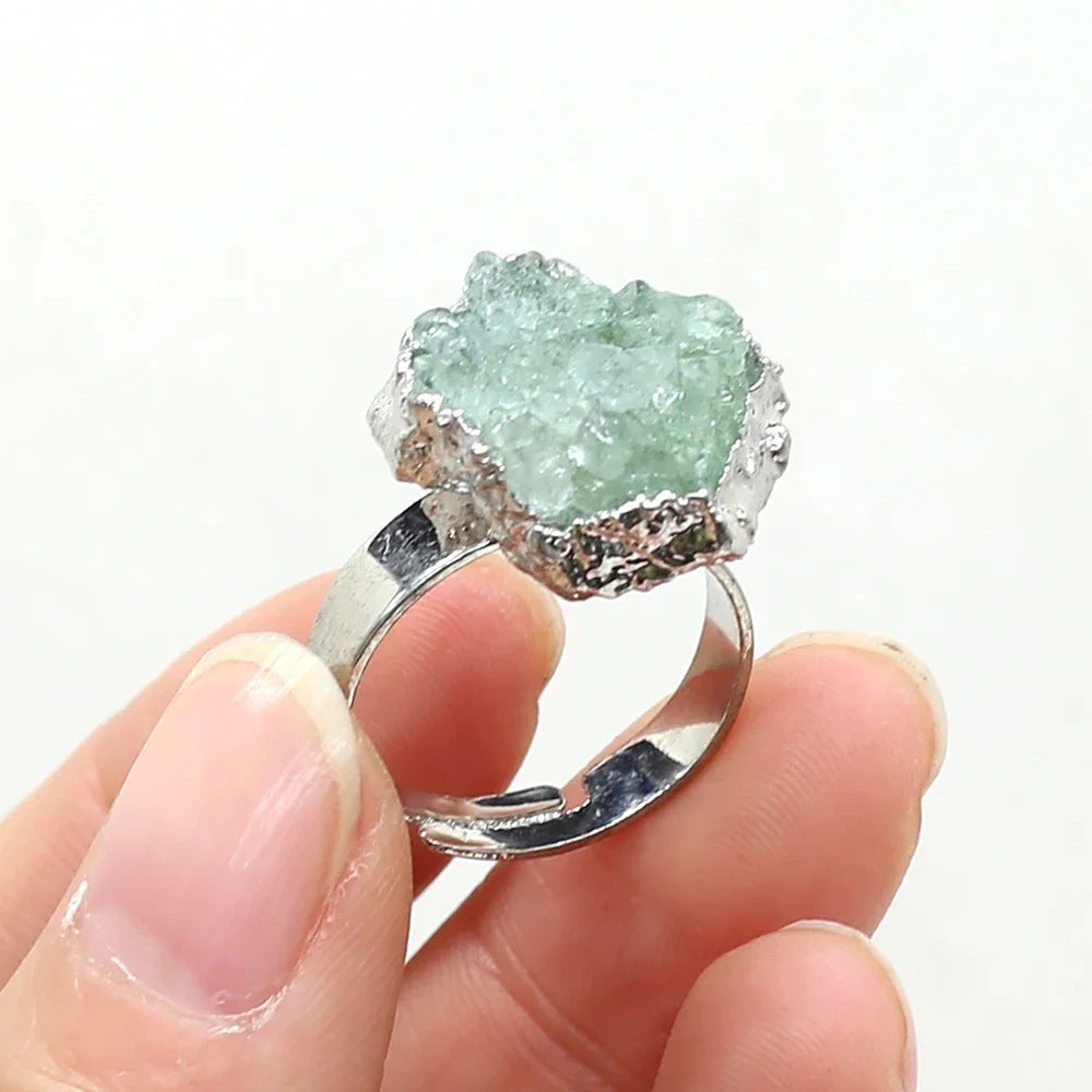 Ring with a green crystal held in a hand against a white background