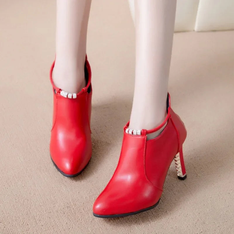 Red high-heeled shoes worn with white leggings on a beige carpet.