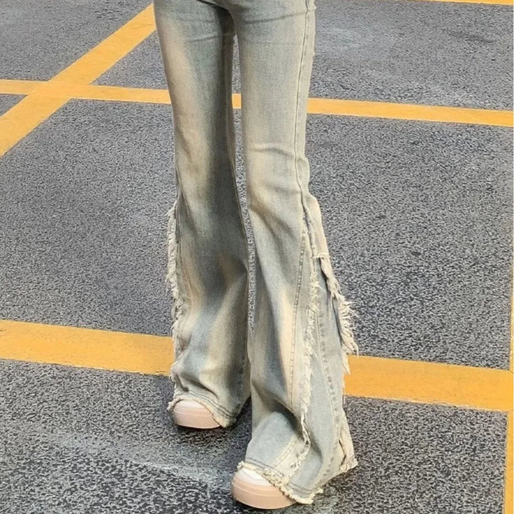 Light blue flared denim jeans with raw frayed hem and stacked distressed rips