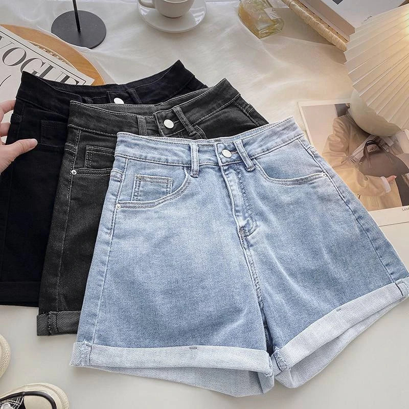 Light blue denim shorts on a white surface with black and gray jeans in the background.