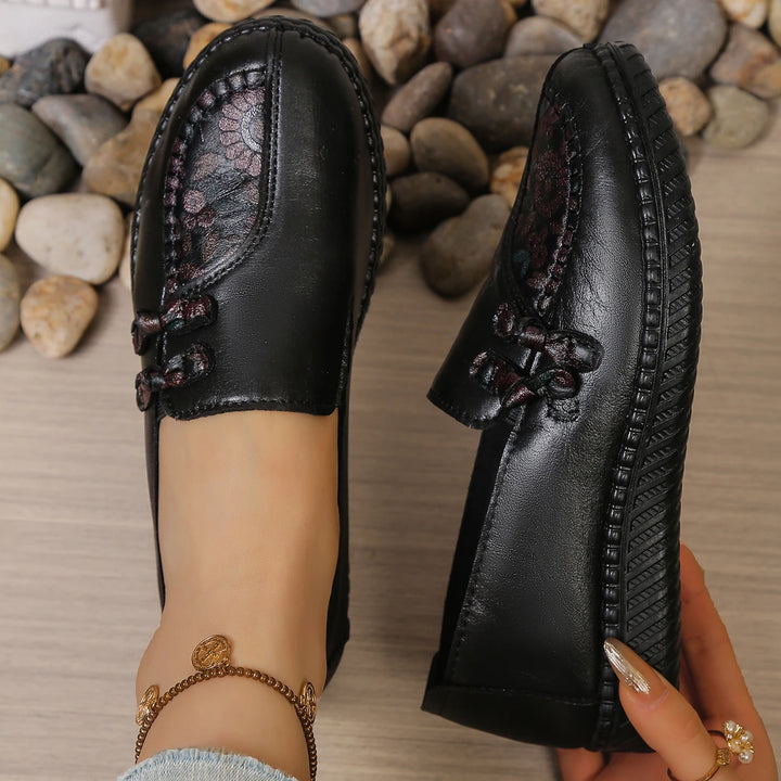 Black leather slip-on mules with butterfly-knot bow, low profile sole and textured tread