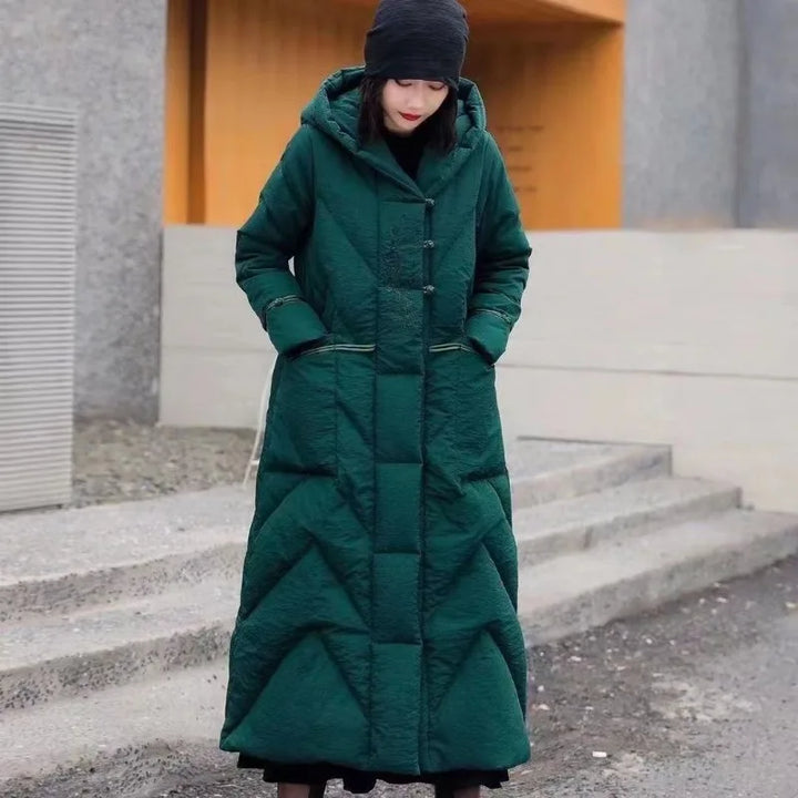 Person wearing a long green coat standing on steps outdoors.