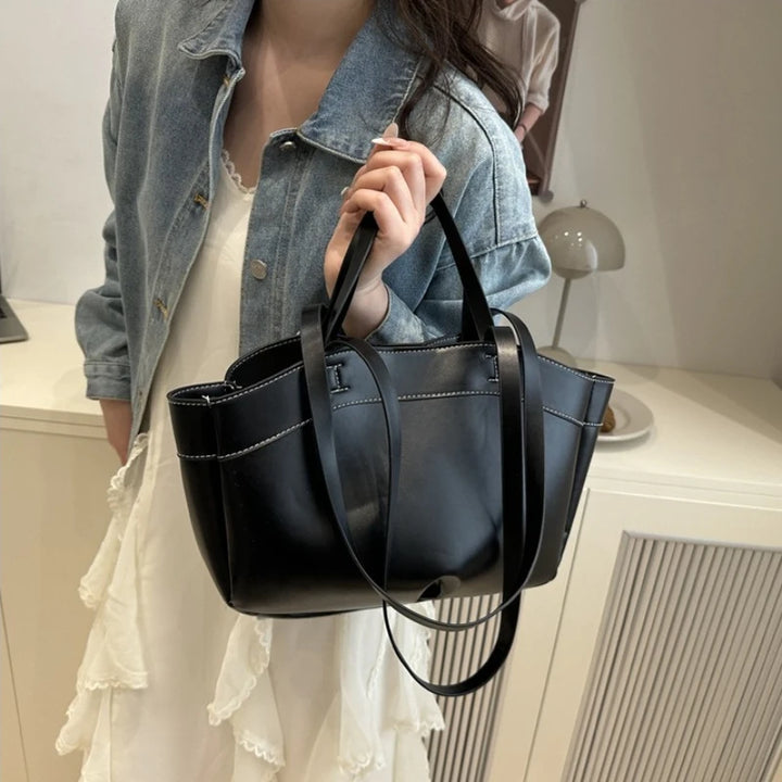 Person holding a black handbag in an indoor setting