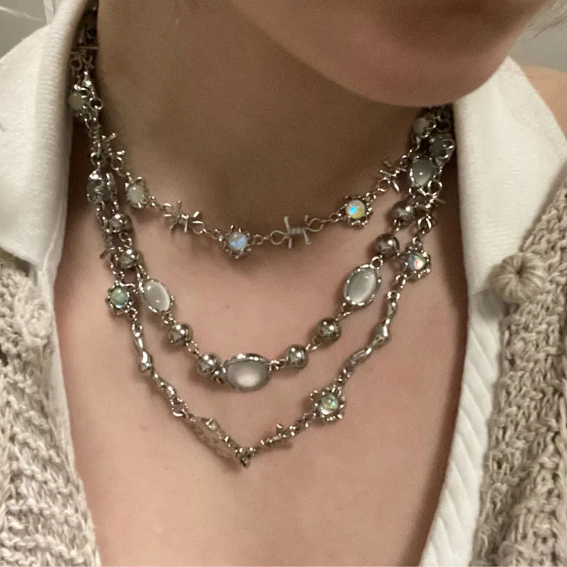 Close-up of a person wearing multiple silver necklaces with gemstones.