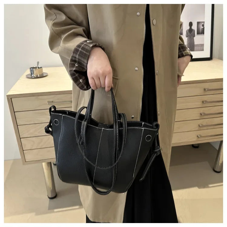 Person holding a black handbag in an indoor setting