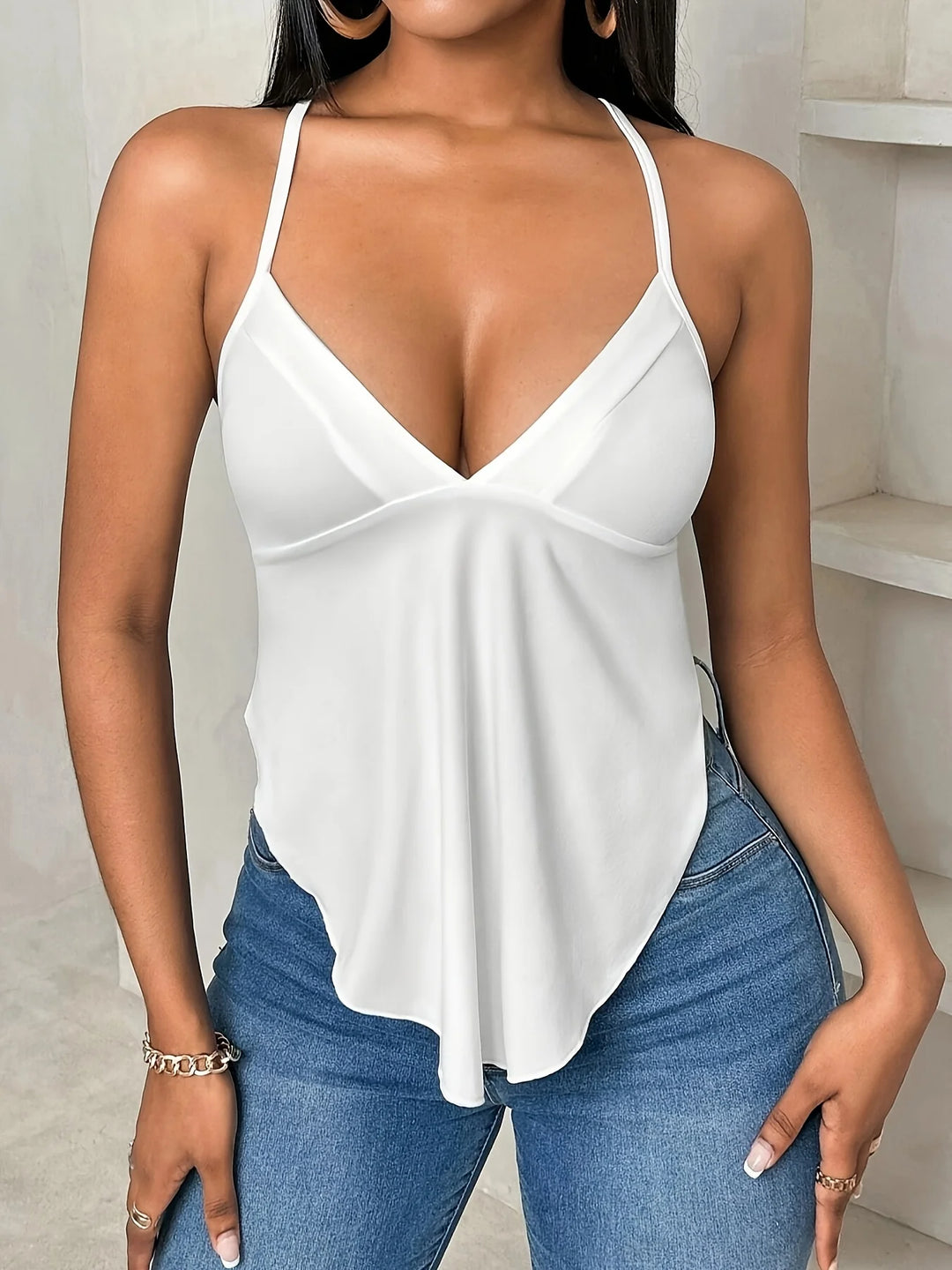 Woman wearing a white top and blue jeans indoors.