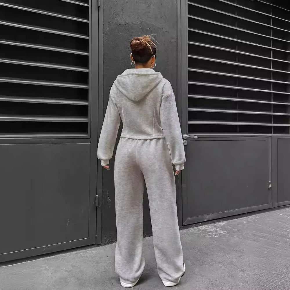 Person wearing a gray tracksuit standing in front of a dark metal gate.