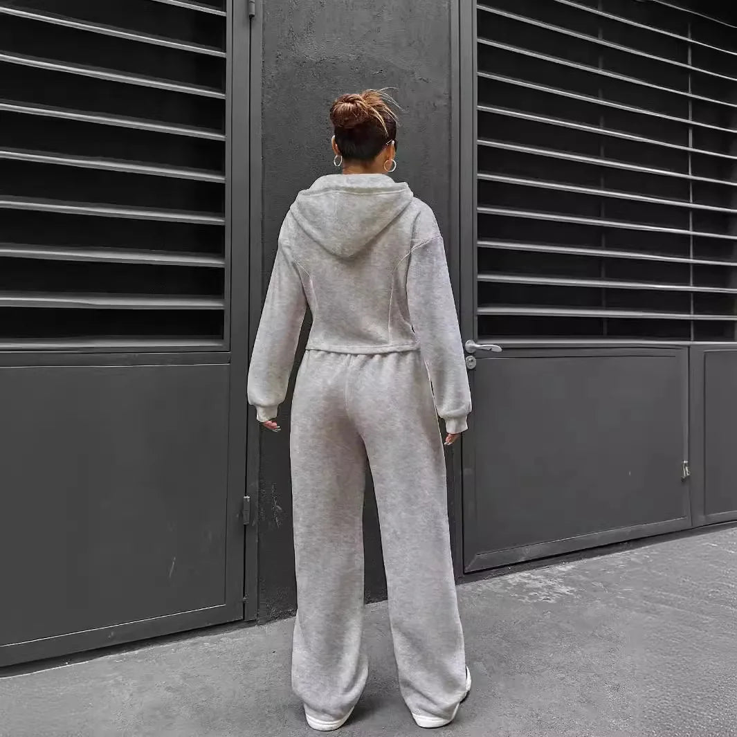Person wearing a gray tracksuit standing in front of a dark metal gate.