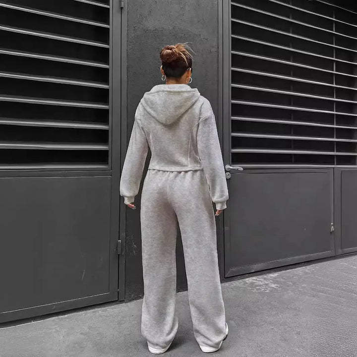 Person wearing a gray tracksuit standing in front of a dark metal gate.