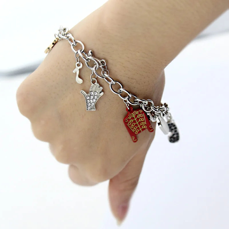 Silver-tone chain bracelet on wrist with red jacket, rhinestone hand charm, small figure charm