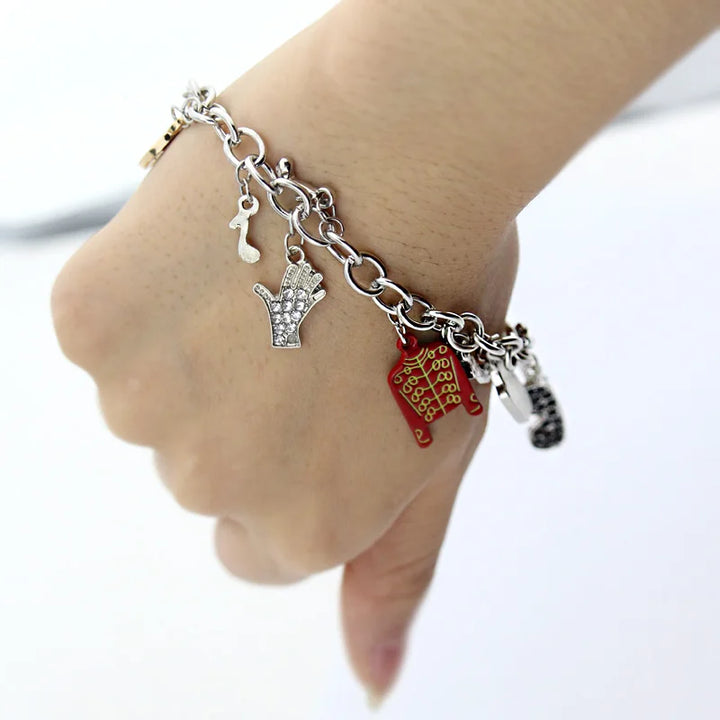 Silver-tone chain bracelet on wrist with red jacket, rhinestone hand charm, small figure charm