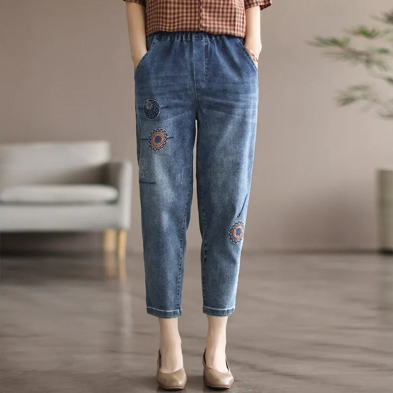Person wearing blue jeans with floral embroidery in a room setting