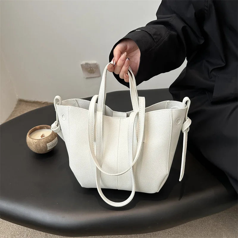 Person holding a white tote bag on a black surface with a neutral background